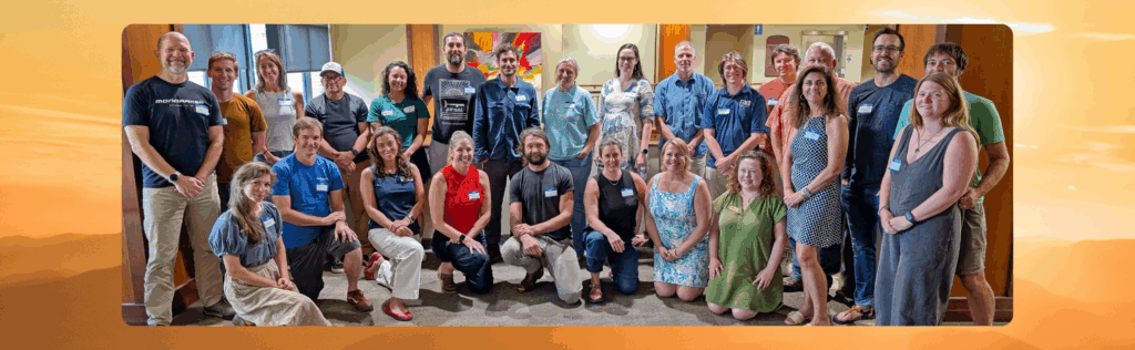 Group photo of the new members of the Waypoint Resilience Cohort standing and sitting together in a bright indoor space, smiling and wearing name tags.