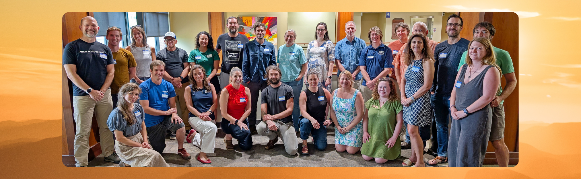 Group photo of the new members of the Waypoint Resilience Cohort standing and sitting together in a bright indoor space, smiling and wearing name tags.
